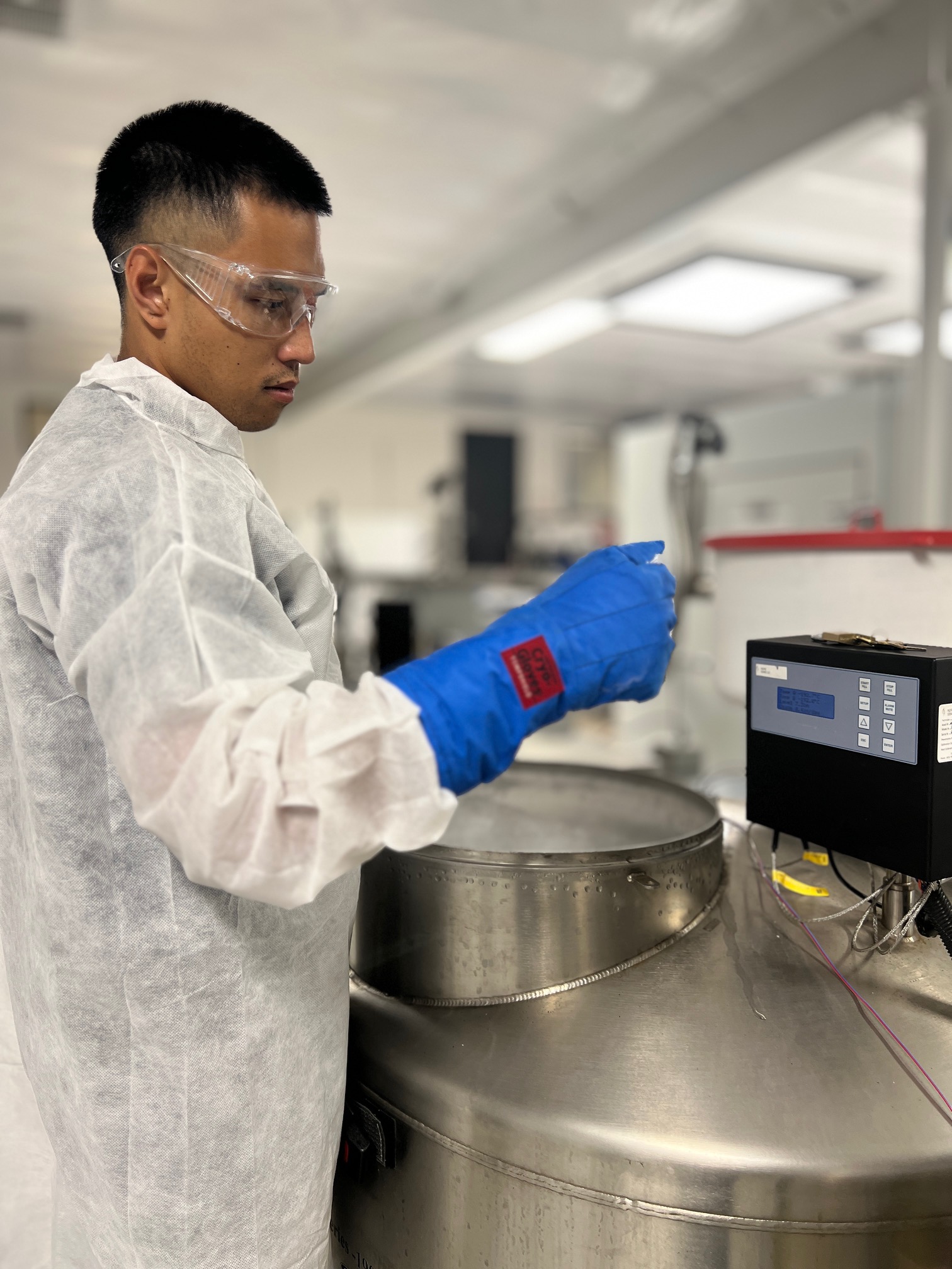 Biorepository technician handling cell bank material in a cryogenic freezer